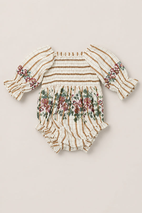 The Baby Madeline Romper in Embroidered Cider Grid by Ivy City Co is an adorable cotton-blend romper in a cream and tan grid pattern, highlighted by intricate floral embroidery, a smocked bodice, sweet puff sleeves with ruffle cuffs, and a cozy bloomer bottom with handy snap closures.