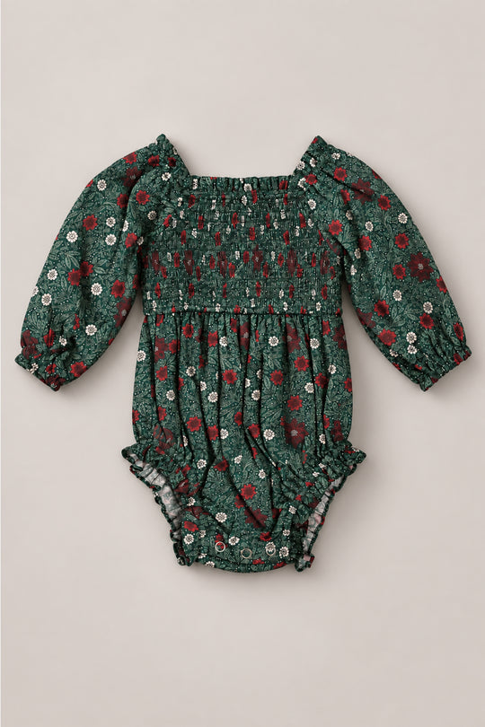 The Baby Madeline Romper in Evergreen Merry Ditsy by Ivy City Co is a charming girls’ Christmas romper for babies, featuring long sleeves, a green fabric with red and white floral print, smocked bodice, elastic cuffs, and ruffled leg openings—all crafted from 100% cotton for festive comfort.