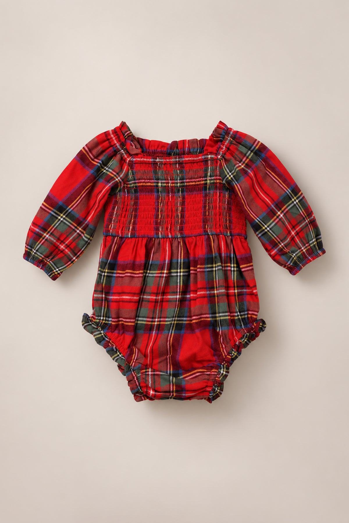The Baby Madeline Romper in Holiday Plaid by Ivy City Co features a classic tartan pattern on soft fabric, with long sleeves, a gathered elastic neckline, smocked bodice, and ruffled leg openings—making it the perfect holiday outfit for your little one.