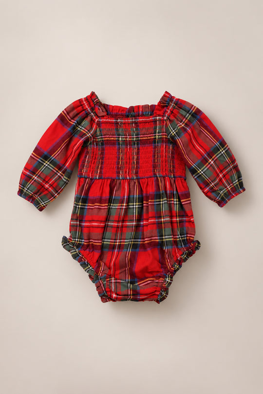 The Baby Madeline Romper in Holiday Plaid by Ivy City Co features a classic tartan pattern on soft fabric, with long sleeves, a gathered elastic neckline, smocked bodice, and ruffled leg openings—making it the perfect holiday outfit for your little one.