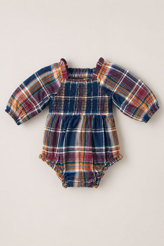 The Baby Madeline Romper in Midnight Plaid by Ivy City Co showcases long puff sleeves and a multicolored plaid pattern in shades of blue, orange, red, and yellow. Delicate ruffle details accent the shoulders and leg openings, adding extra charm to this adorable outfit.
