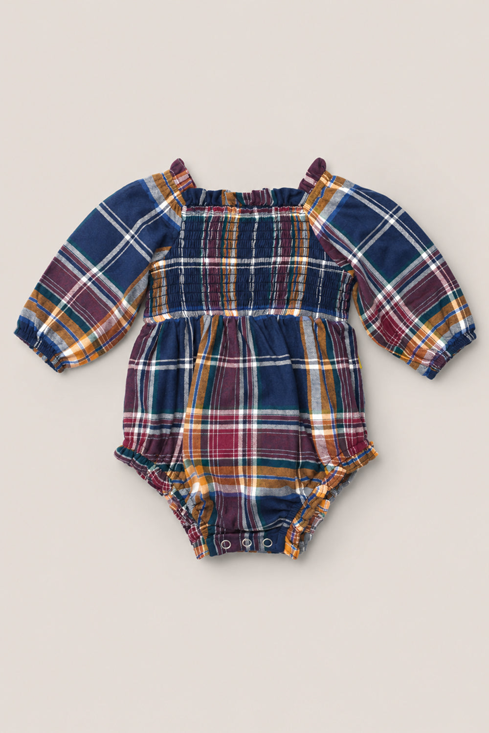 The Ivy City Co Baby Madeline Romper in Midnight Plaid features long sleeves, a vibrant blue, red, yellow, and white plaid pattern, a smocked bodice for extra charm, and gathered elastic at the chest and leg openings.