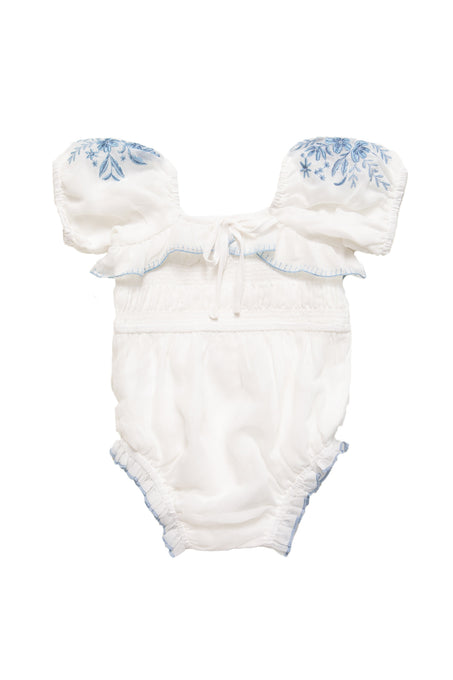 The Ivy City Co Baby Mae Romper in White with Blue Floral features ruffled off-shoulder sleeves, a smocked bodice, blue floral embroidery on the sleeves, and light blue stitching along the edges.