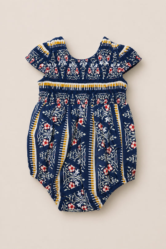 The Baby Marlow Romper in Navy Fleur by Ivy City Co is a navy floral romper featuring short sleeves, yellow accents, and a white and red floral pattern. It showcases smocking across the chest, elastic leg openings, and is crafted from soft cotton to keep your little one comfortable.