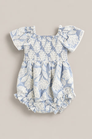 The Ivy City Co Baby Ophelia Romper in Mosaic Embroidery features light blue fabric, short sleeves, white leaf embroidery, smocked chest and waist, and ruffled leg openings for a soft Mom and Me matching look.