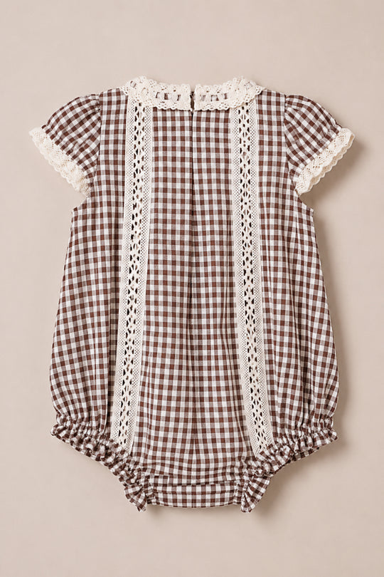 The Ivy City Co Baby Palermo Romper in Hickory Gingham features a charming brown and white gingham pattern, short sleeves, delicate lace trim on the sleeves and collar, vertical lace accents down the front, gathered leg openings, and convenient snap closures at the bottom—all crafted from a soft cotton-blend for all-day comfort.