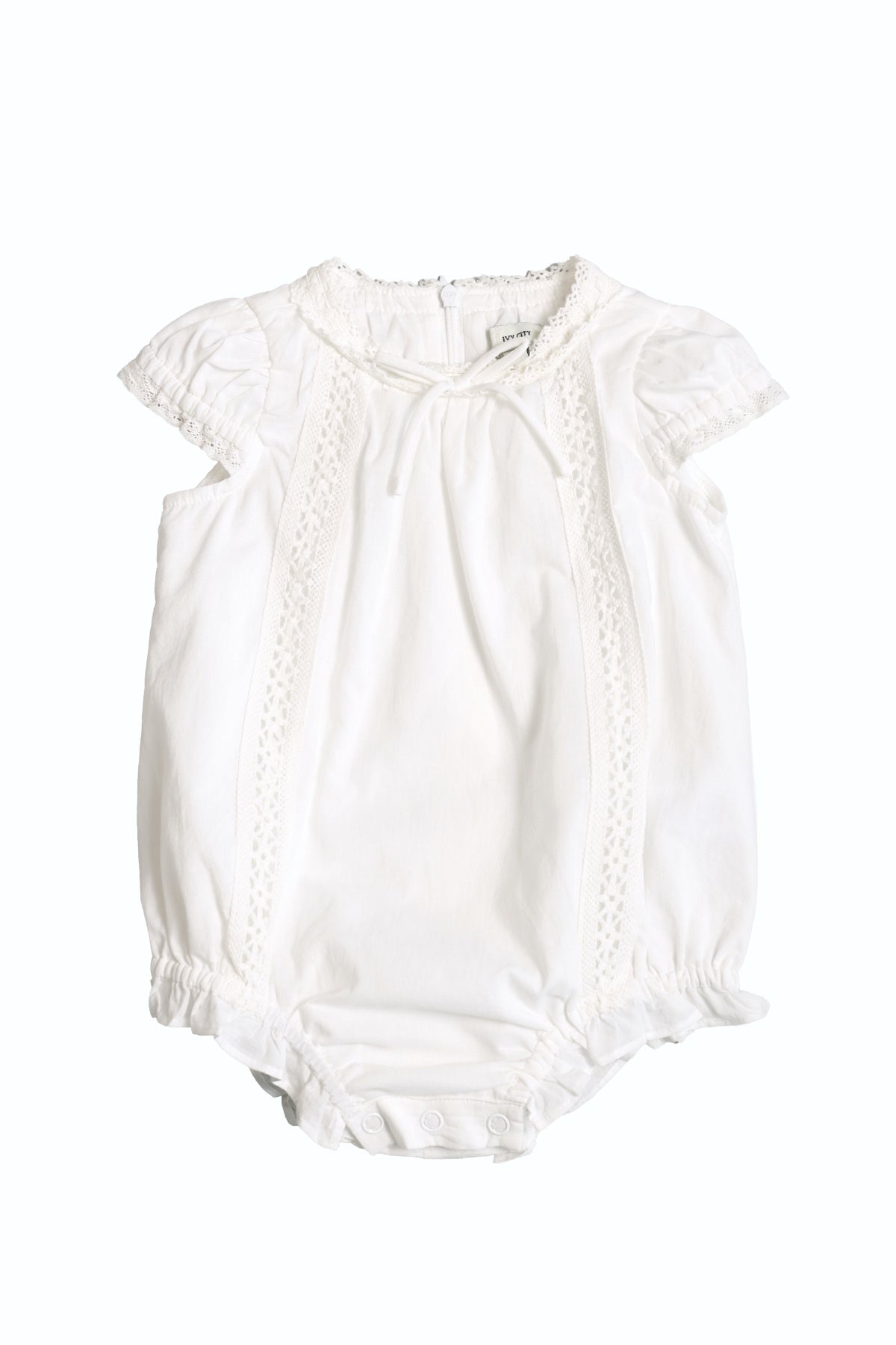 The Baby Palermo Romper in White by Ivy City Co features short puff sleeves, lace trim, bottom snap buttons for easy changes, and soft lightweight fabric—perfect for summer comfort and adorable Mom and Me matching looks.