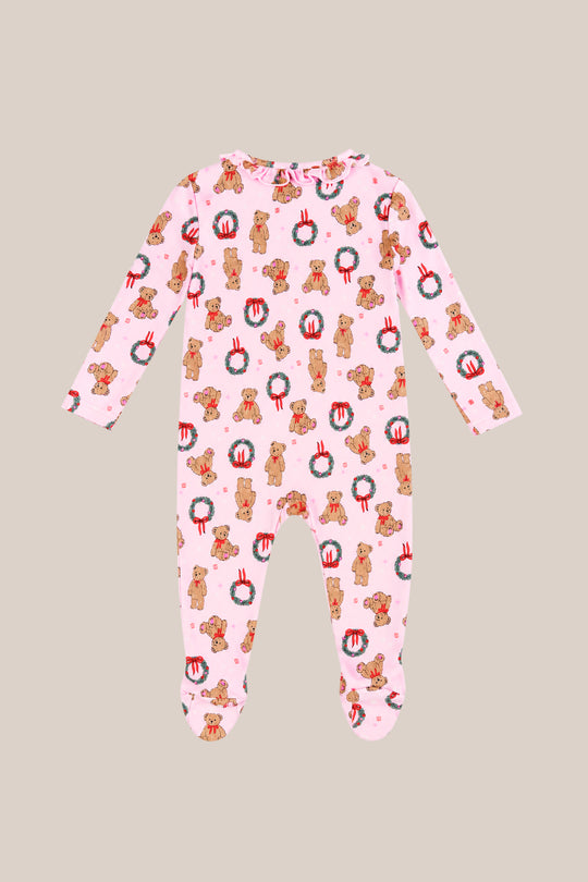 The Baby So Soft Onesie in Teddy Bear Wreaths by Ivy City Co is made from soft cotton-modal knit with a teddy bear and wreath print. These cozy, long-sleeve holiday pajamas are shown laid flat on a beige background.