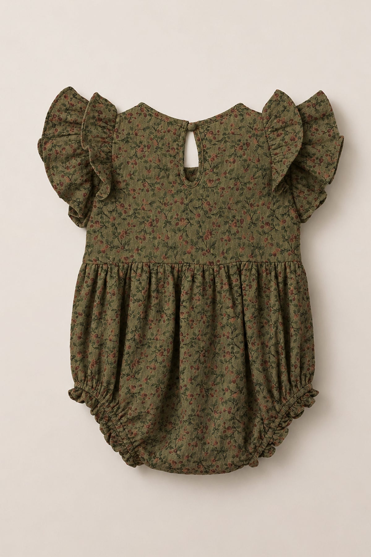 The Ivy City Co Baby Hattie Romper in Woodland Floral features an olive green hue with a delicate small floral print, short flutter sleeves, a gathered waist, elastic leg openings, and a back button closure. Crafted from soft cotton, this romper offers everyday comfort and charming style.