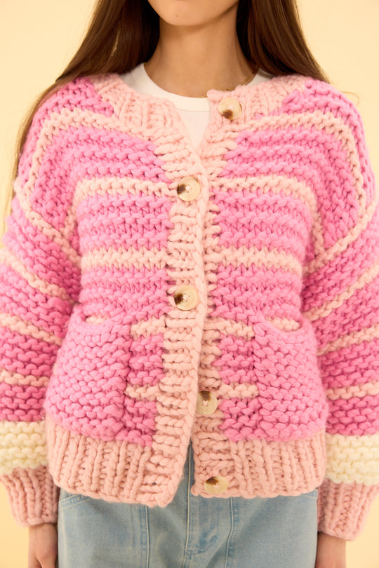 Pink and beige striped cardigan worn by a person on a yellow background