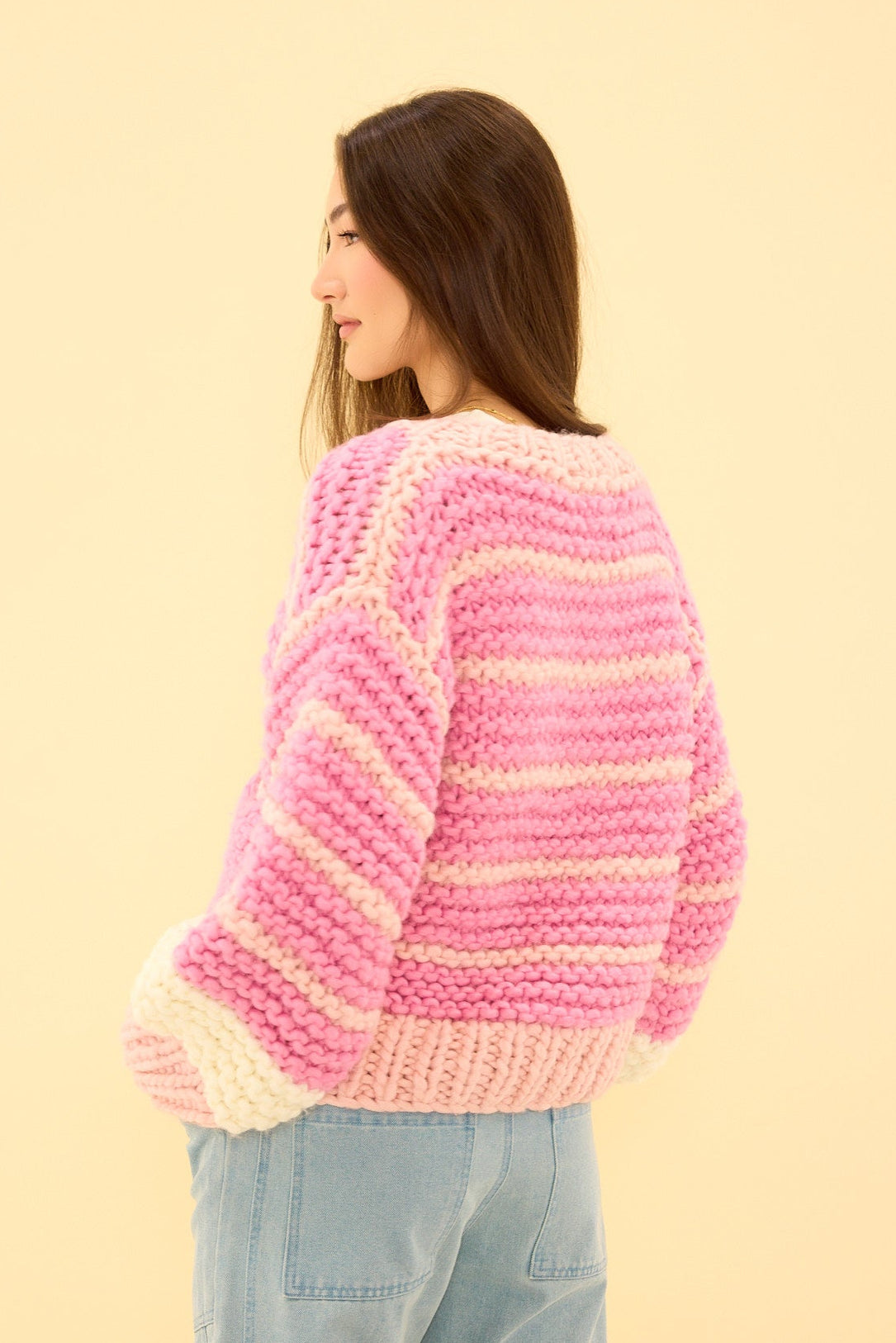 Woman wearing a pink and white striped sweater on a beige background