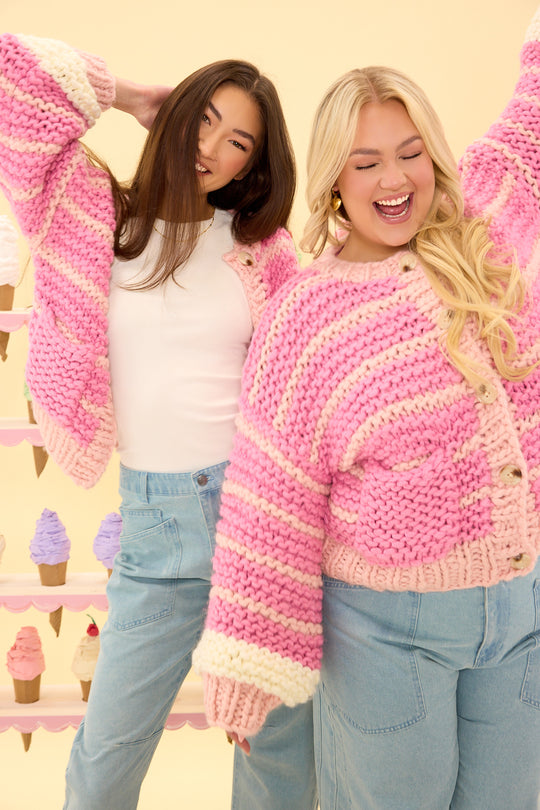 Two women wearing pink and white striped sweaters with ice cream cones in the background.