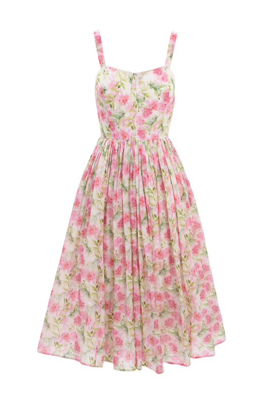 The Ivy City Co Ballerina Tank Dress in Pink Floral features a sleeveless, fitted bodice, a flared midi-length skirt, and a light pink floral pattern on a white background.