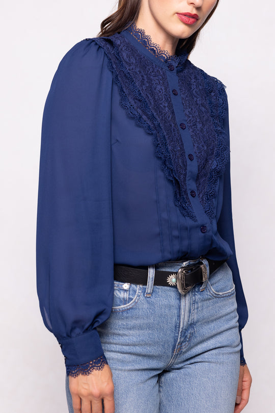 Navy blue blouse with lace details worn by a person on a white background