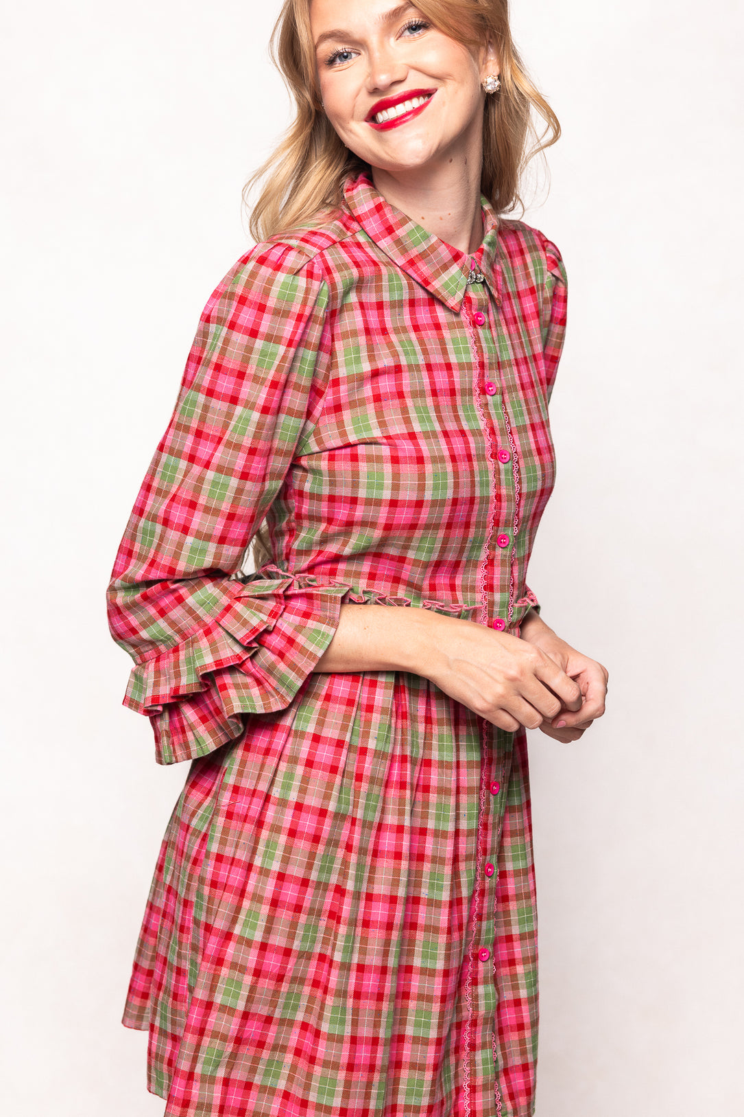 Woman wearing a red and green plaid dress against a white background