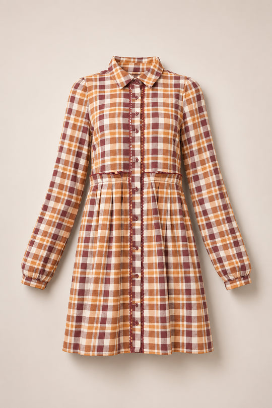 The Bowie Long Sleeve Dress in Spiced Plaid by Ivy City Co features a button-down design with long sleeves, a fitted waist, and a collared neckline. Crafted for both style and practicality, this nursing-friendly dress displays shades of brown, yellow, and cream in its plaid cotton fabric and is accented with decorative lace trim along the buttons.