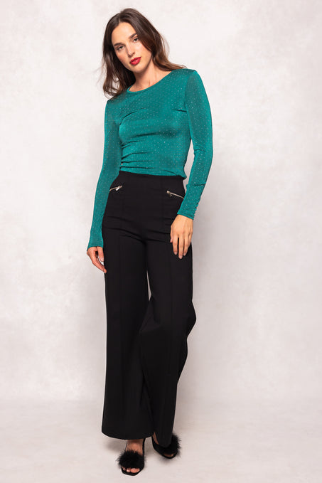 Woman wearing a teal top and black pants on a white background