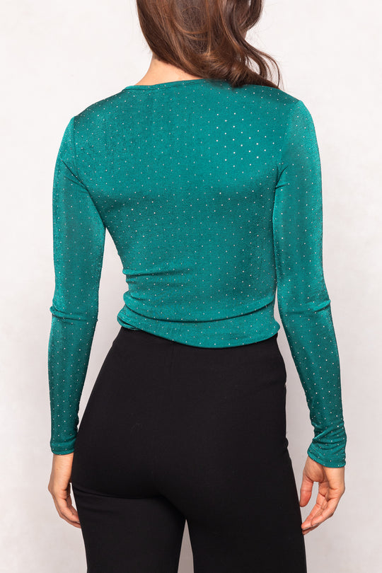 Green long-sleeve top worn by a person on a white background