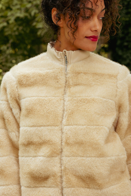 Person wearing a beige fleece jacket with a blurred green background
