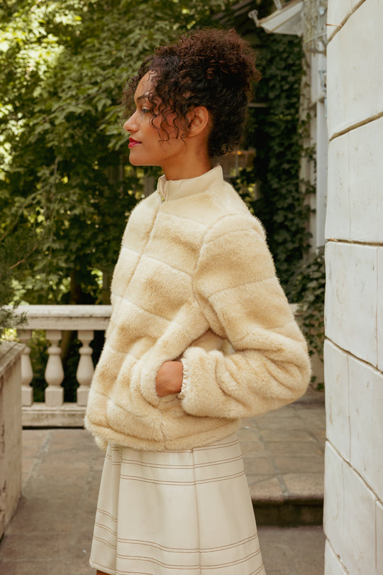 Woman wearing a cream-colored fluffy jacket outdoors