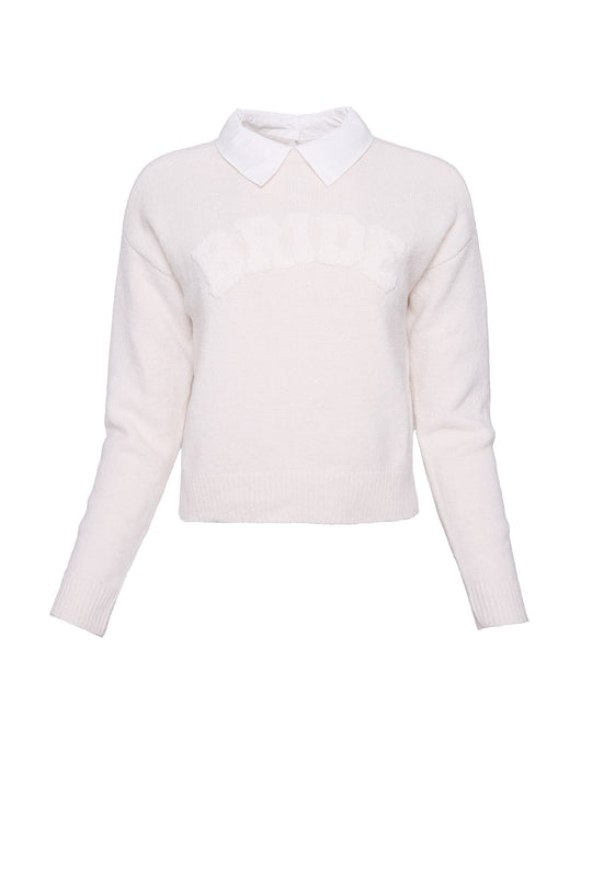 An oatmeal “Bride Sweater” by Ivy City Co is styled over a white collared shirt, featuring the word “BRIDE” in large letters across the chest. This makes it an ideal engagement outfit, photographed against a plain white background.