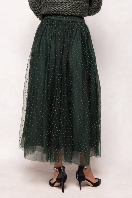 Green polka dot skirt worn by a person on a white background