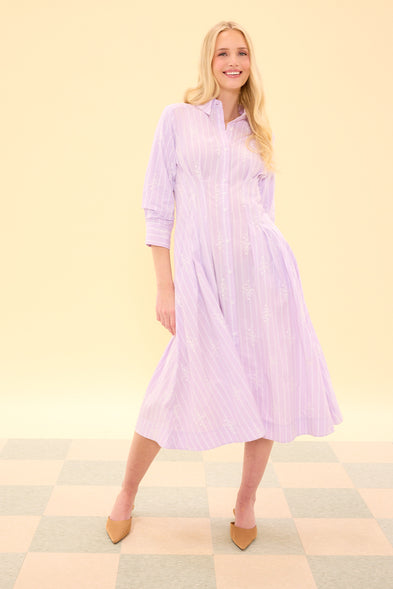 Woman wearing a light purple dress on a checkered floor with a beige wall background