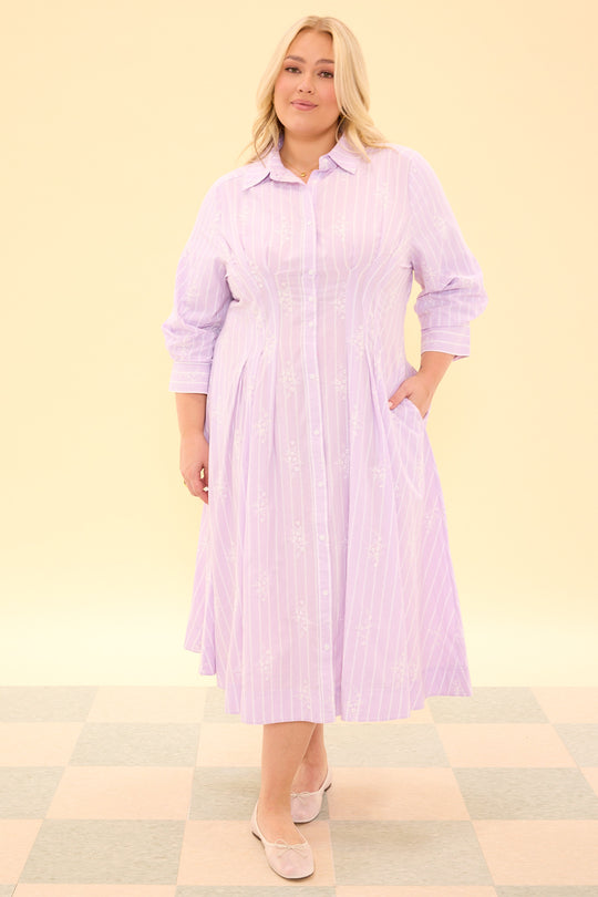 Woman wearing a light purple striped dress on a beige background