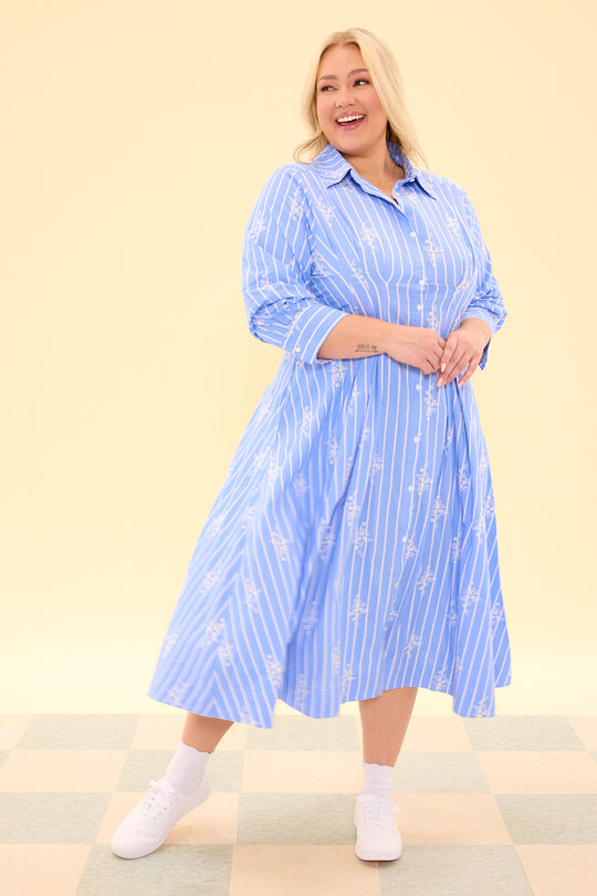 Woman wearing a blue striped dress on a beige background