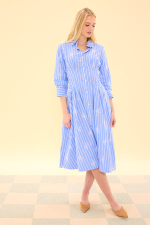 Woman wearing a blue striped dress on a checkered floor with a beige wall background