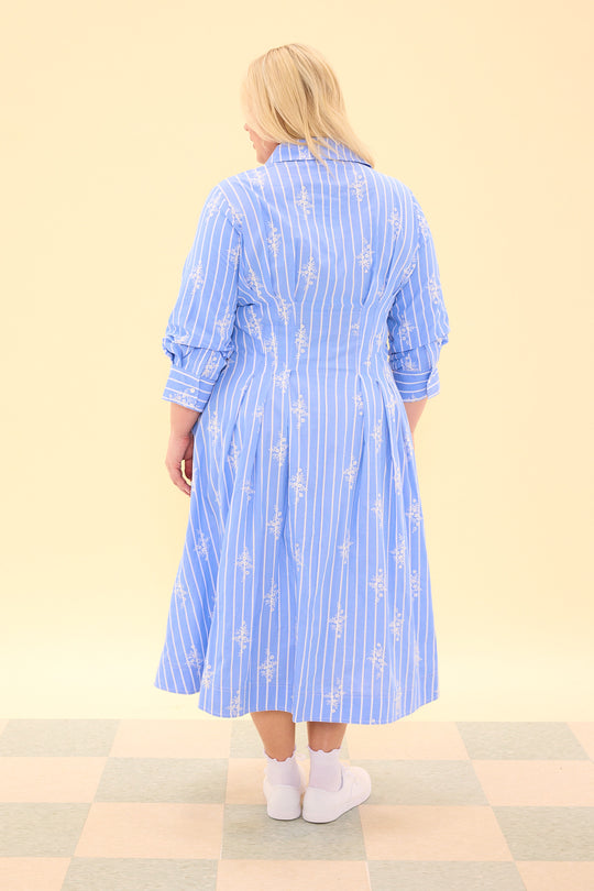 Woman wearing a blue striped dress with floral patterns on a beige background