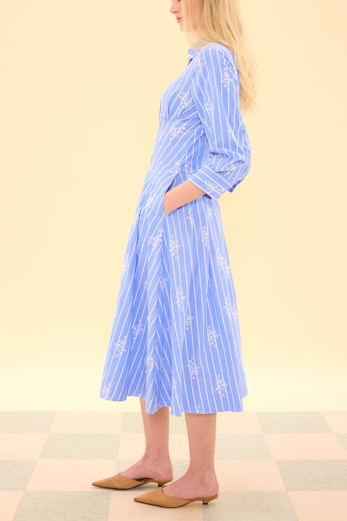 Woman wearing a blue striped dress on a beige background