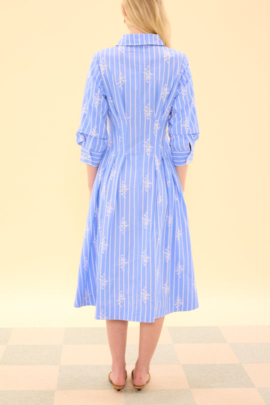 Woman wearing a blue and white striped dress on a beige background