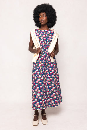 Woman wearing a patterned dress with a white cardigan on a plain background
