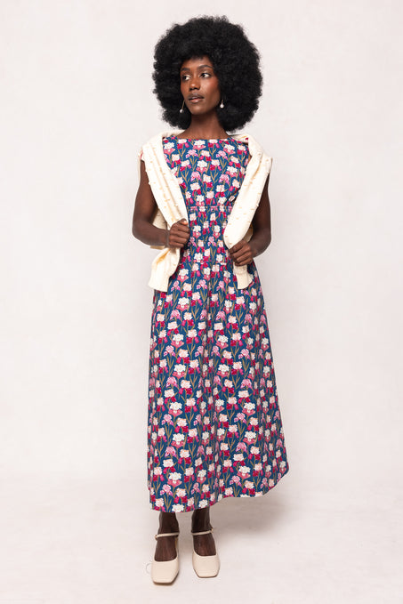 Woman wearing a patterned dress with a white cardigan on a plain background