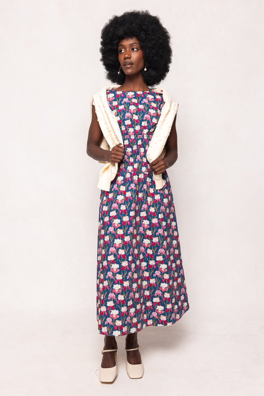 Woman wearing a patterned dress with a white cardigan on a plain background