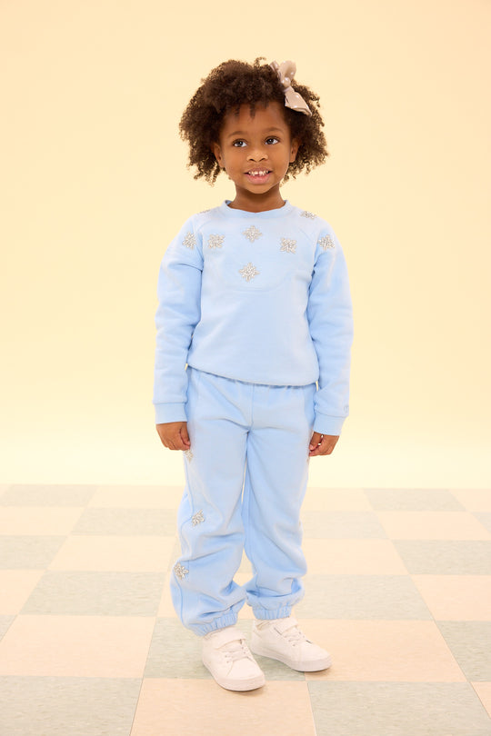 Child wearing a light blue outfit with star patterns on a checkered floor.
