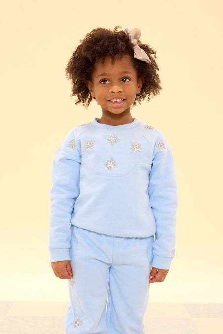 Child wearing a light blue outfit with star patterns on a checkered floor.