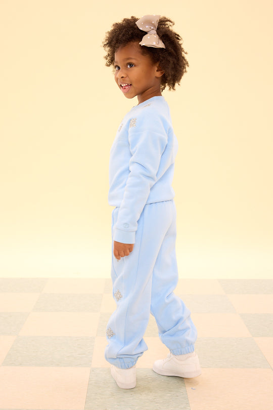 Child wearing a light blue onesie on a beige background
