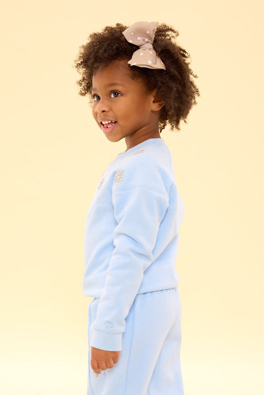 Child wearing a light blue onesie on a beige background