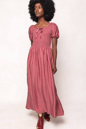Woman wearing a pink dress with puffed sleeves on a white background