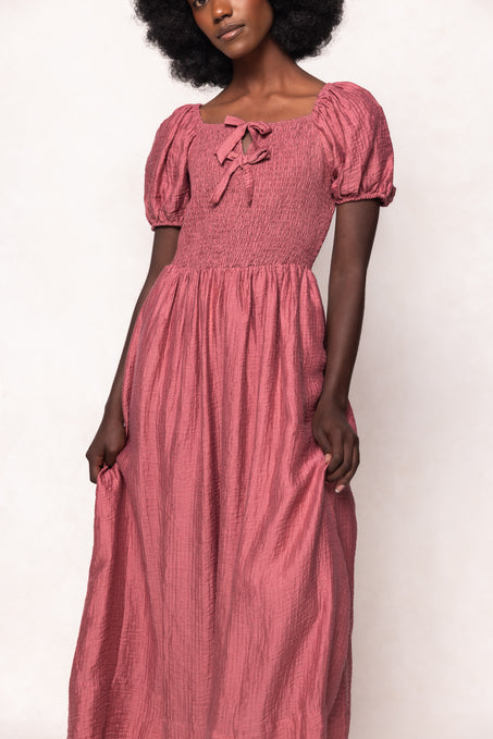 Woman wearing a pink dress with puffed sleeves against a white background