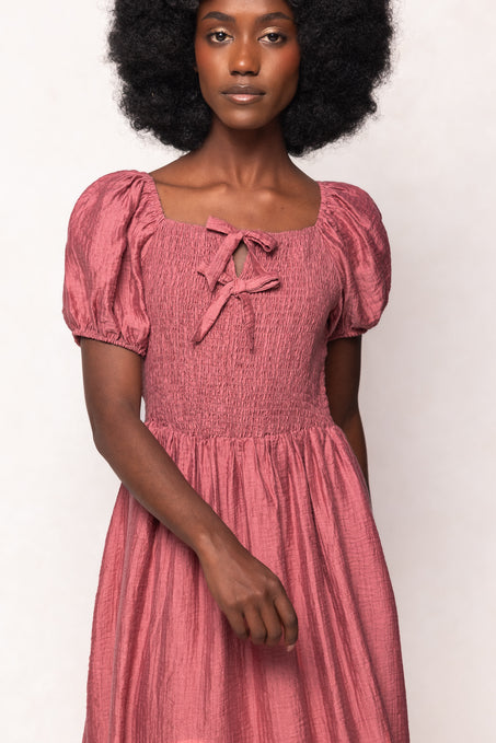 Woman wearing a pink dress with puffed sleeves against a white background
