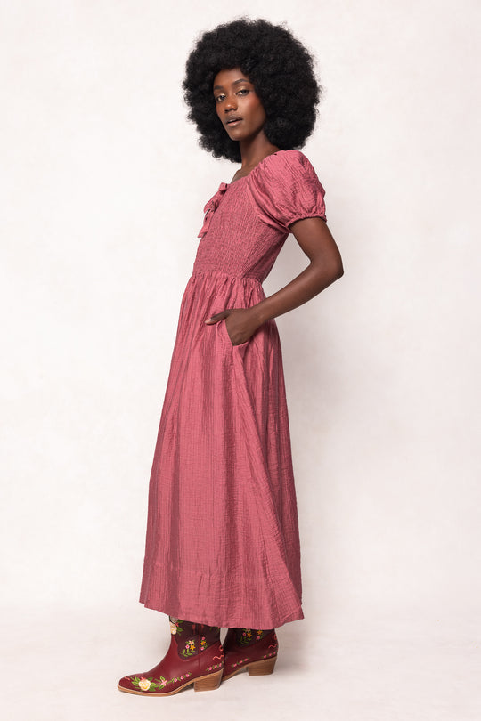 Woman wearing a pink dress with puffed sleeves against a white background