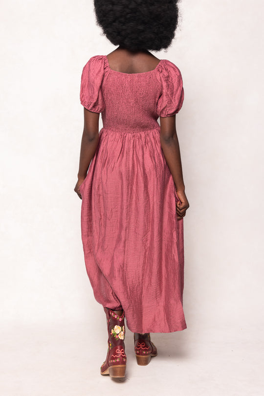 Person wearing a pink dress with puffed sleeves on a white background