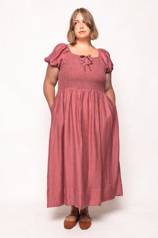 Woman wearing a pink dress with puffed sleeves on a white background