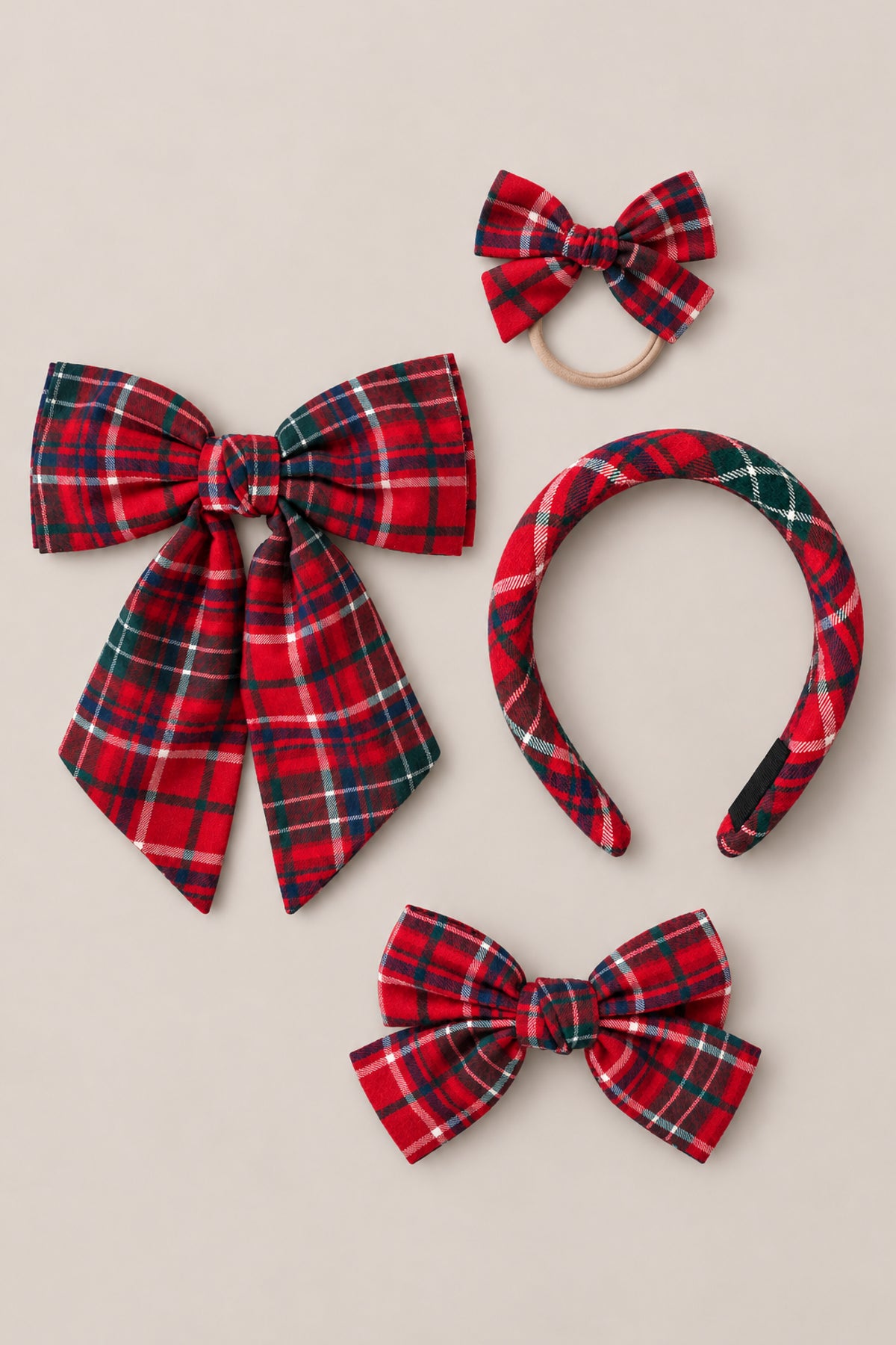 Four hair accessories from Ivy City Co’s Hair Bows in Christmas Cheer Plaid collection—a large Christmas bow, a small bow on an elastic band, a plaid headband, and a medium bow clip—are displayed together on a neutral background. These festive pieces make ideal holiday photo accessories, adding a delightful seasonal flair to any outfit.