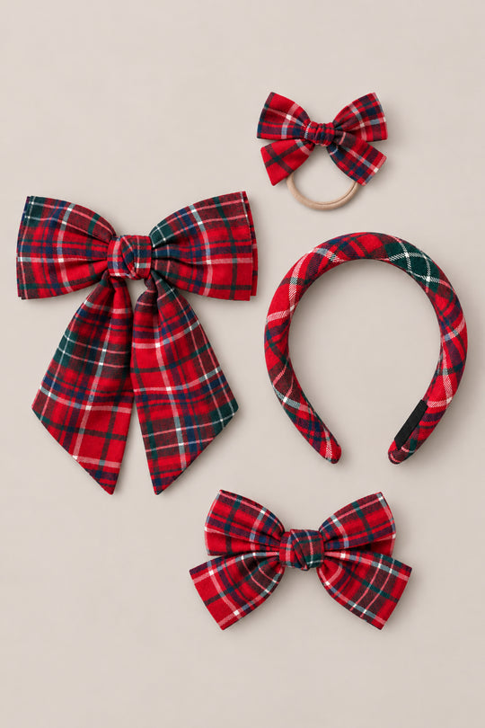 Four hair accessories from Ivy City Co’s Hair Bows in Christmas Cheer Plaid collection—a large Christmas bow, a small bow on an elastic band, a plaid headband, and a medium bow clip—are displayed together on a neutral background. These festive pieces make ideal holiday photo accessories, adding a delightful seasonal flair to any outfit.