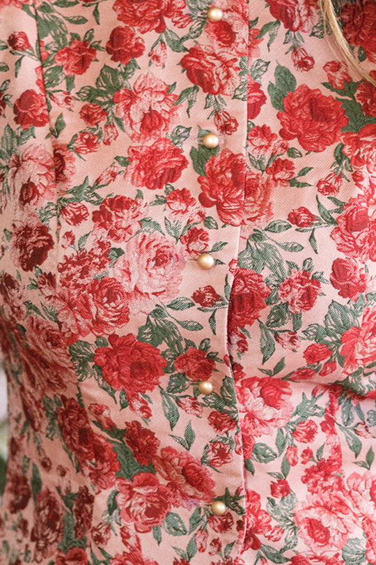 Close-up of the Ciara Vest in Antiquity Rose by Ivy City Co, featuring a pink and red floral pattern with gold buttons—an elegant, nursing-friendly piece perfect for holiday parties.