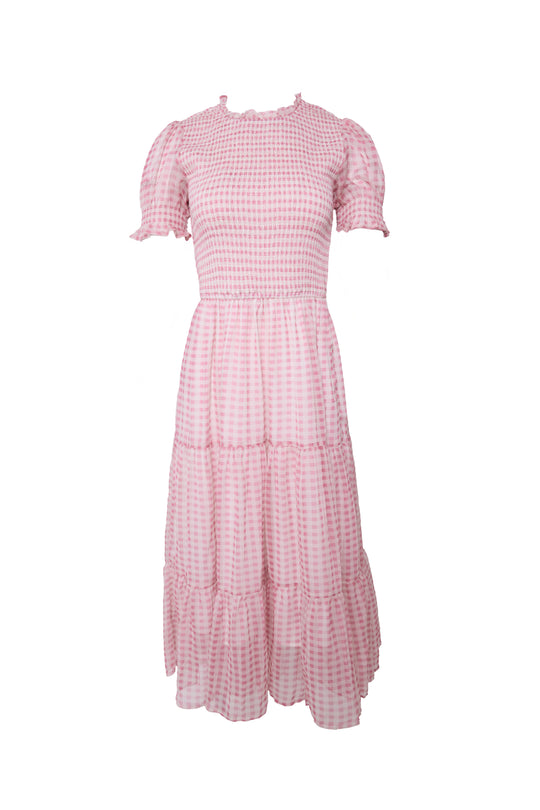 The Cordelia Dress in Desert Rose Gingham by Ivy City Co features pink and white gingham, short puff sleeves, a smocked bodice, a round neckline, and a tiered knee-length skirt. This maternity-friendly dress is perfect for a soft, feminine look.